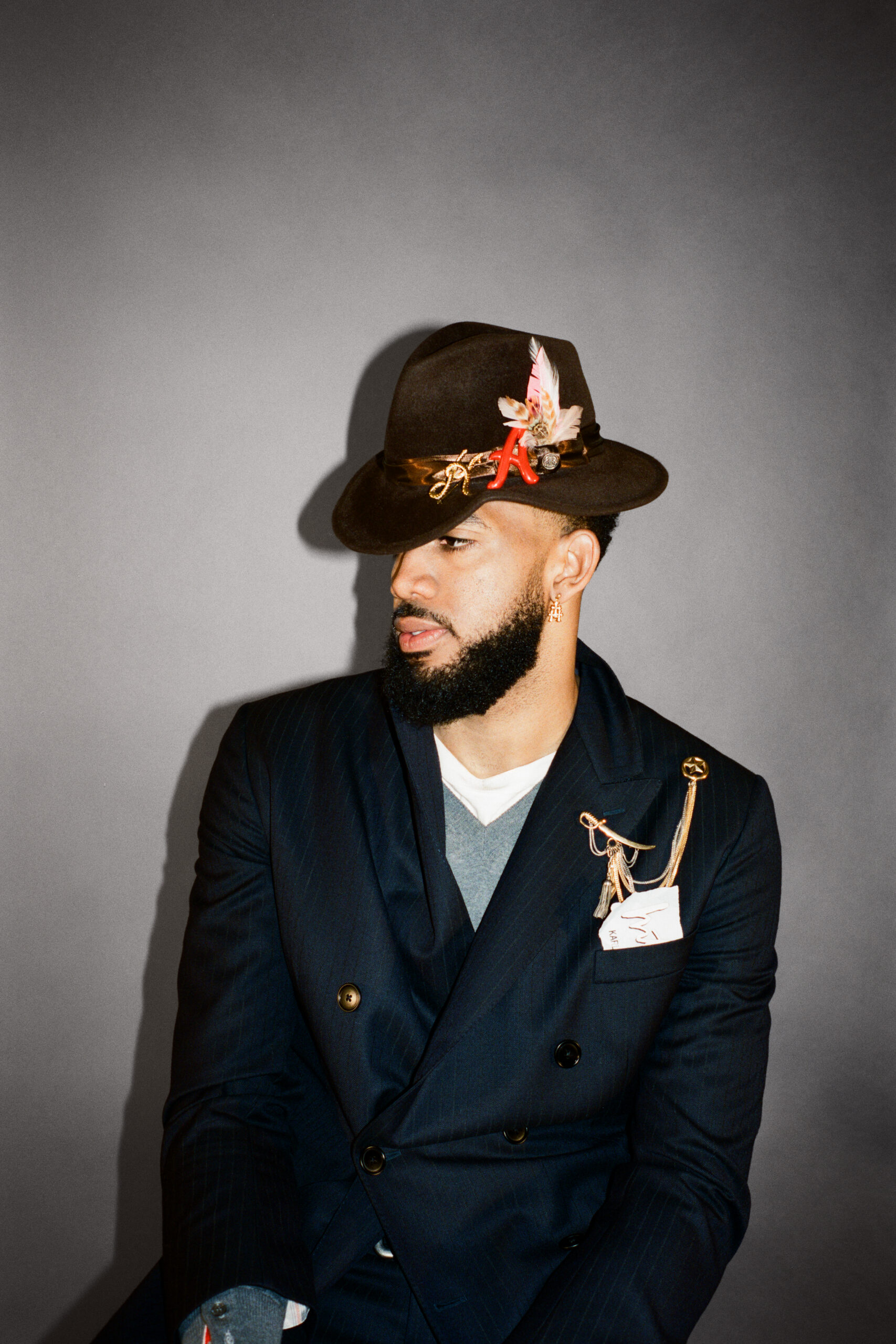 Karl-Anthony Towns looks off to the side wearing a brown fedora.