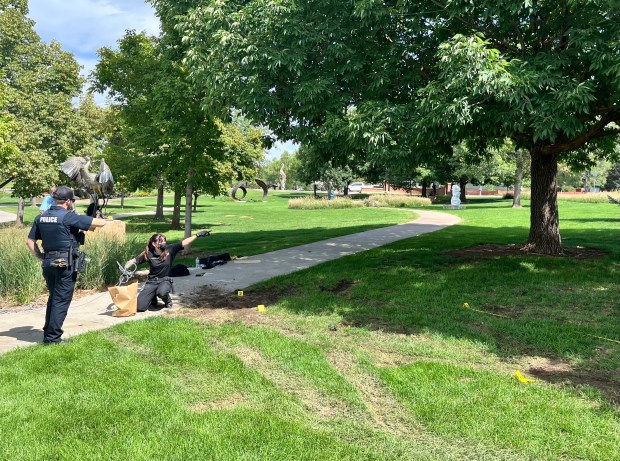 LPD Crime Scene Analyst Sydney Salazar (crouching) collects a rope that was left on scene to submit into evidence. On her left is Officer Ryan, and to their right are tire tracks marked by yellow evidence markers. (Sharla Steinman/ Loveland Reporter-Herald.