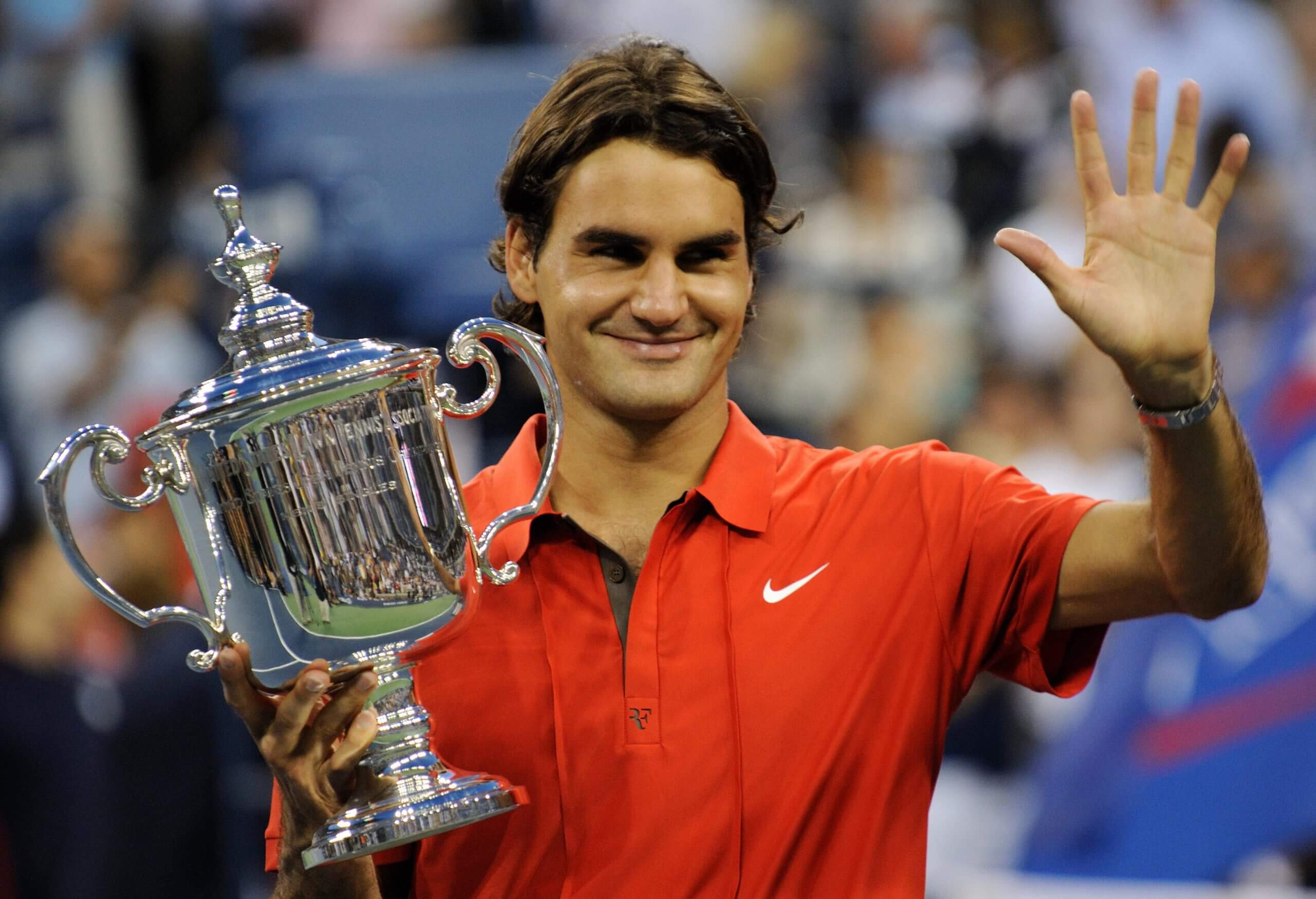 Roger Federer poses with the U.S. Open men's singles trophy wearing a red polo.