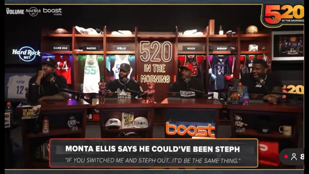 Four men sitting at a desk with microphones, labeled "520 In The Morning," and sports memorabilia on shelves behind them.