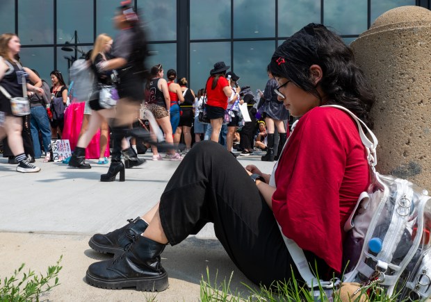 Baltimore resident Alainah Reyes, 24, sits patiently outside M&T Bank Stadium as fans pack the line to enter BTS' "Arirang" World Tour in Baltimore, the group's 16th stop on the tour. (Ryan Bowie/Staff)