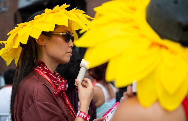 Virginia Beach resident Zharlyn Garcia, 38, cools down with a personal fan as she stands in line outside of M&T Bank Stadium five hours ahead of the BTS concert. (Ryan Bowie/Staff)