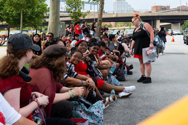 Hundreds of BTS fans sit on a curb outside of M&T Bank Stadium waiting for the BTS concert to begin. (Ryan Bowie/Staff)