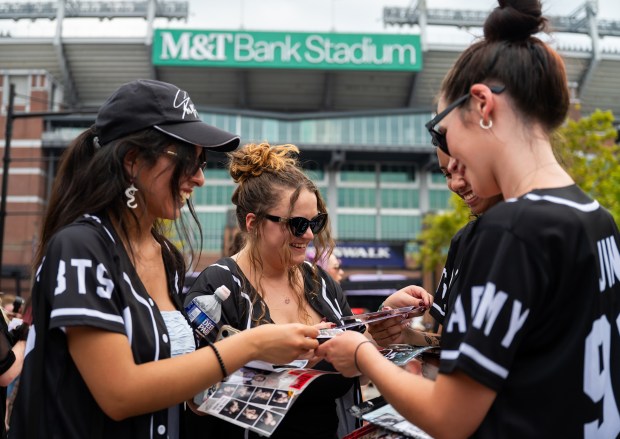 From left, Valeria Hernandez, 21, Abby Peyton, 23, Stephanie Taylor, 22, and Mallory Yancey, 22, all from Virginia, trade BTS freebies, including stickers and other keepsakes, outside M&T Bank Stadium four hours before the concert. (Ryan Bowie/Staff)