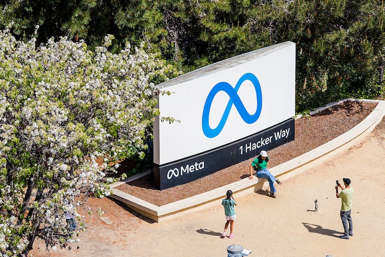FILE - Visitors take photos at a sign outside Meta headquarters March 26, 2026, in Menlo Park, Calif. (AP Photo/Noah Berger, File)