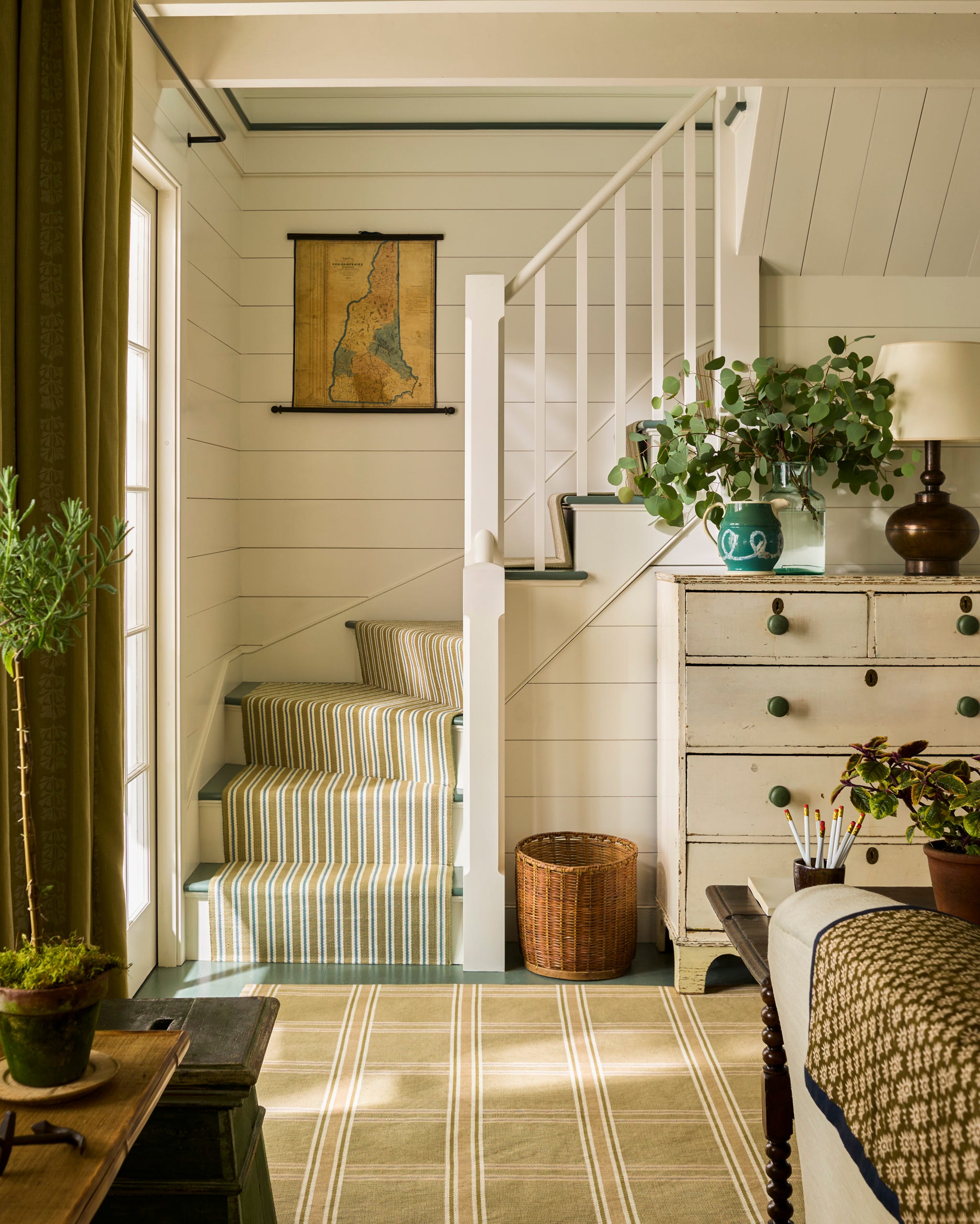 New Hampshire Lake Cottage by Schafer & Company Bright and airy interior with striped stairs, green decor, and a vintage map on the wall.
