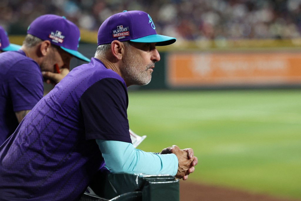 Arizona Diamondbacks manager Torey Lovullo in a purple and turquoise hat looking onto the field.