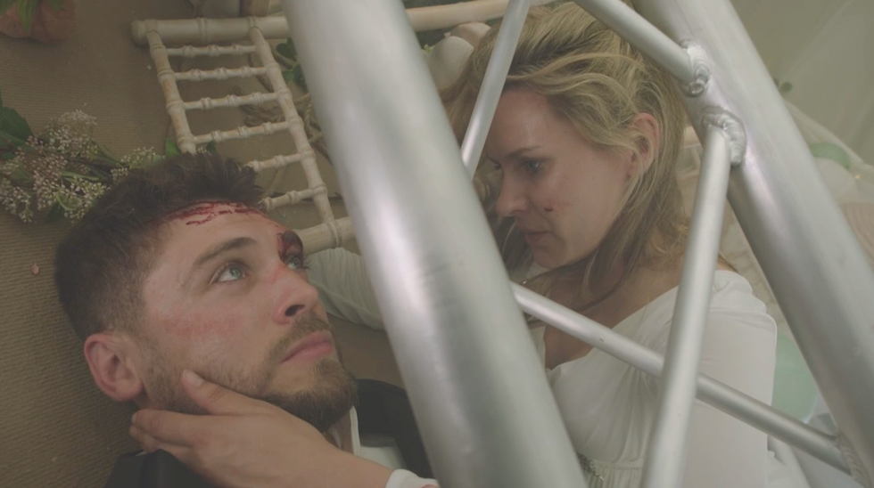 joe tate is trapped under some poles as dawn fletcher lies next to him and caresses his face in a scene of emmerdale