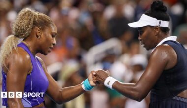 Serena Williams bumps fists with Venus Williams during their first round match at the Cincinnati Open