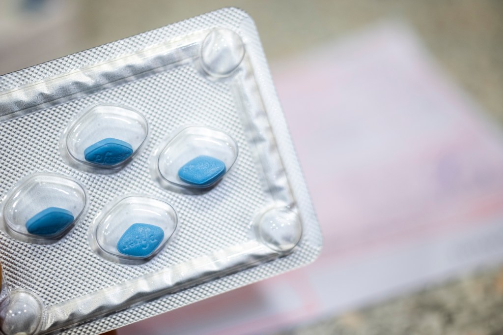 Blister pack of Viagra tablets with a prescription in the background.