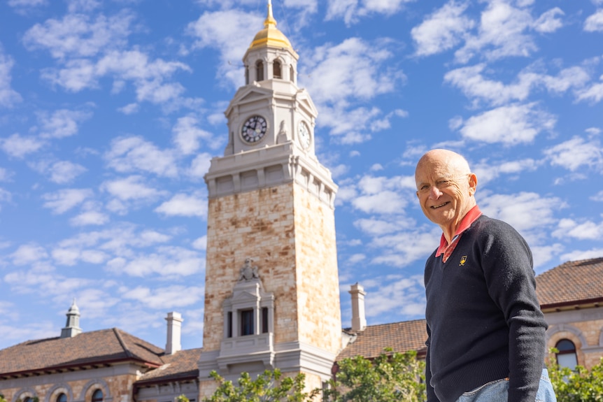 A man standing in front of a heritage building with a clocktower in Kalgoorlie.  