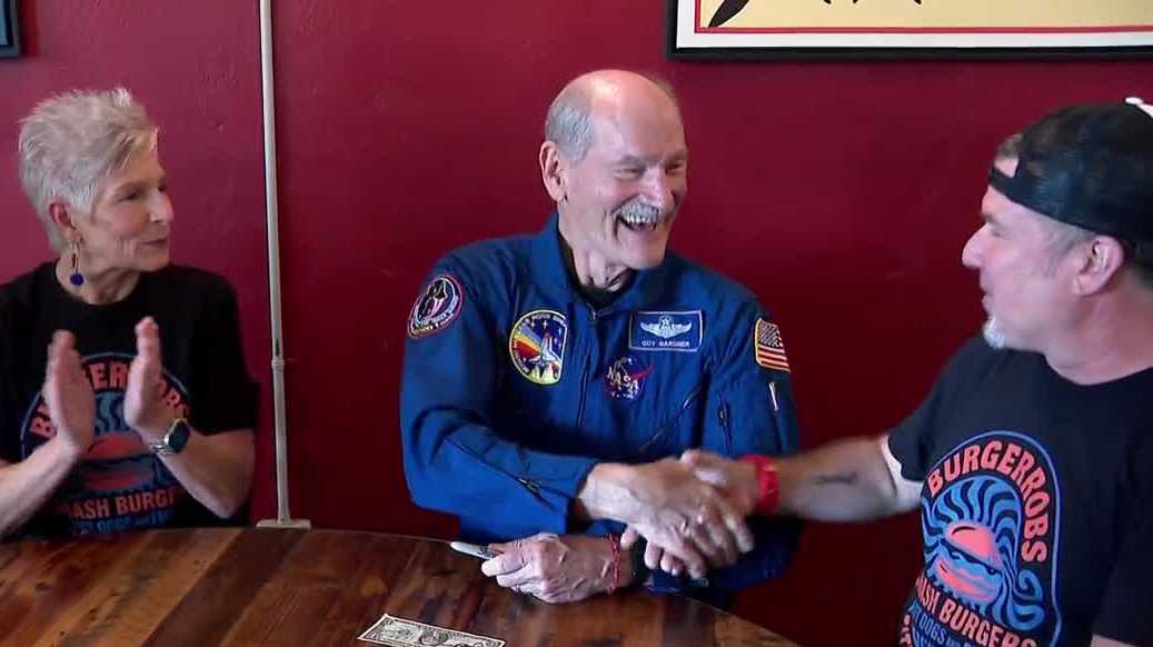 Space Shuttle astronaut adds signature to dollar bill in Florida