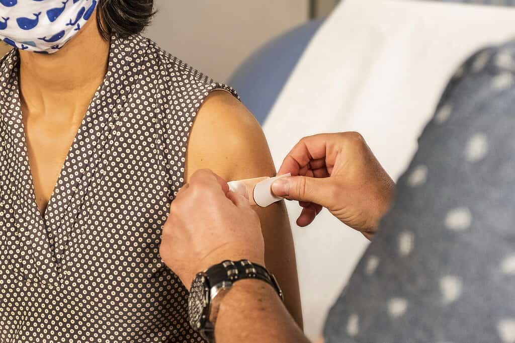 Person who was vaccinated with a healthcare professional applying a bandage.