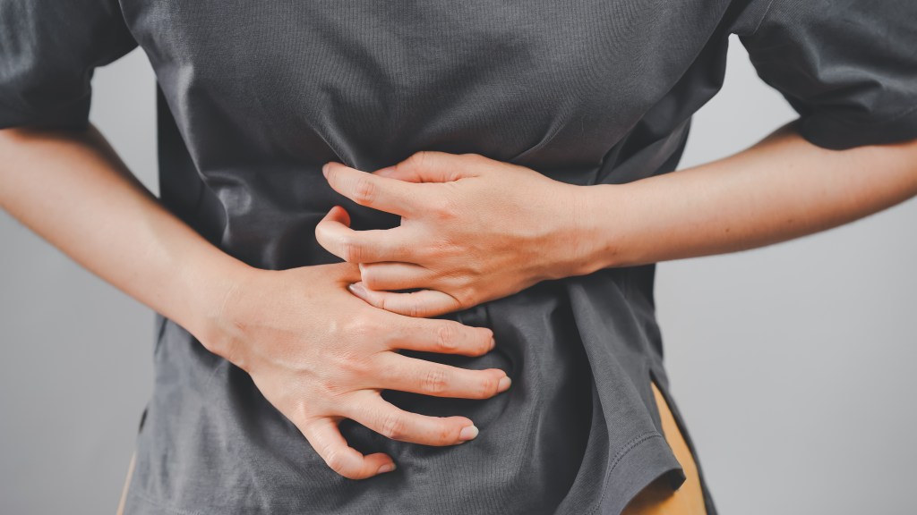 Woman clutching her stomach, indicating abdominal pain or discomfort.