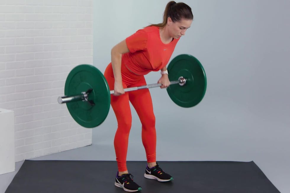 A person in red athletic wear performs a bent-over row exercise with a barbell on a gym mat. A person in red athletic wear performs a bent-over row exercise with a barbell on a gym mat.