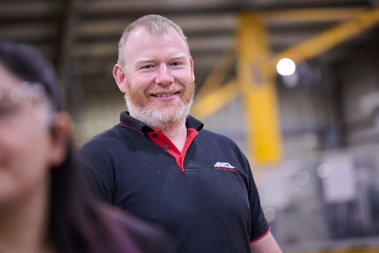 A man in a blue T-shirt is smiling.