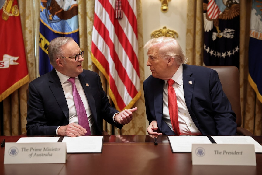 Anthony Albanese and Donald Trump speak while seated on the same side of a long desk.