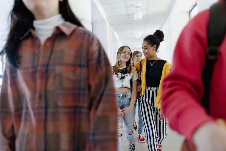 Two girls walk down a school hallway
