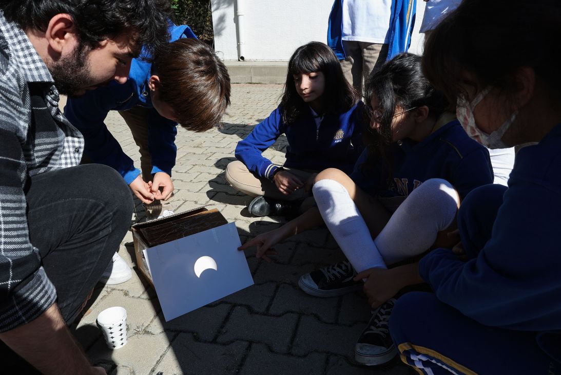 People observe a partial solar eclipse on a paper through a telescope in Ankara, Turkey, on October 25, 2022.