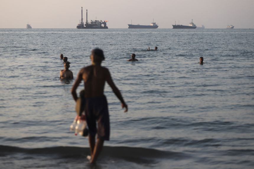 People take a dip in the Strait of Hormuz off Bandar Abbas, Iran, as cargo and commercial vessels lie at anchor on June 8.