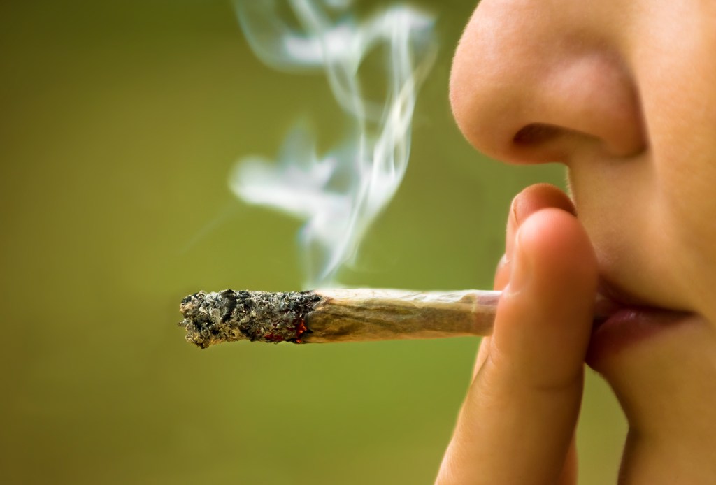 A close-up of a girl smoking marijuana.