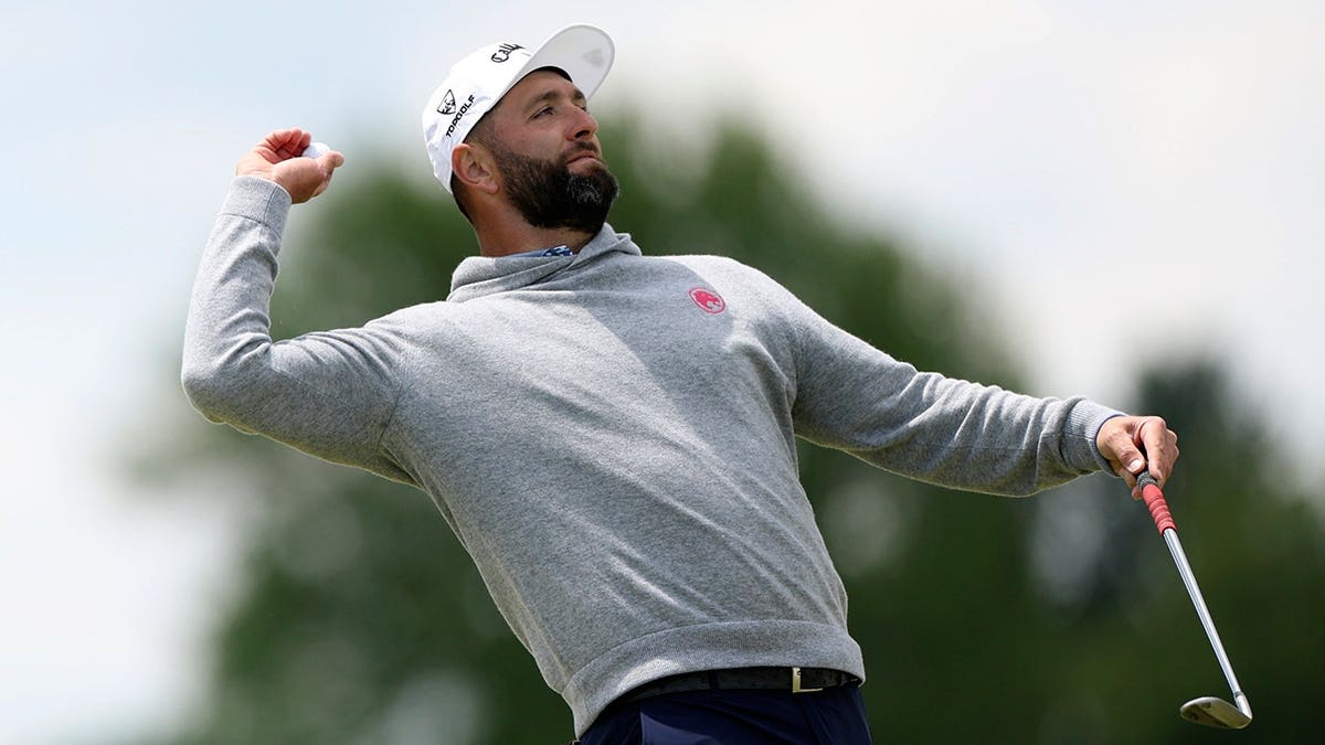 Jon Rahm tossing golf ball toward crowd on second green at Aronimink Golf Club