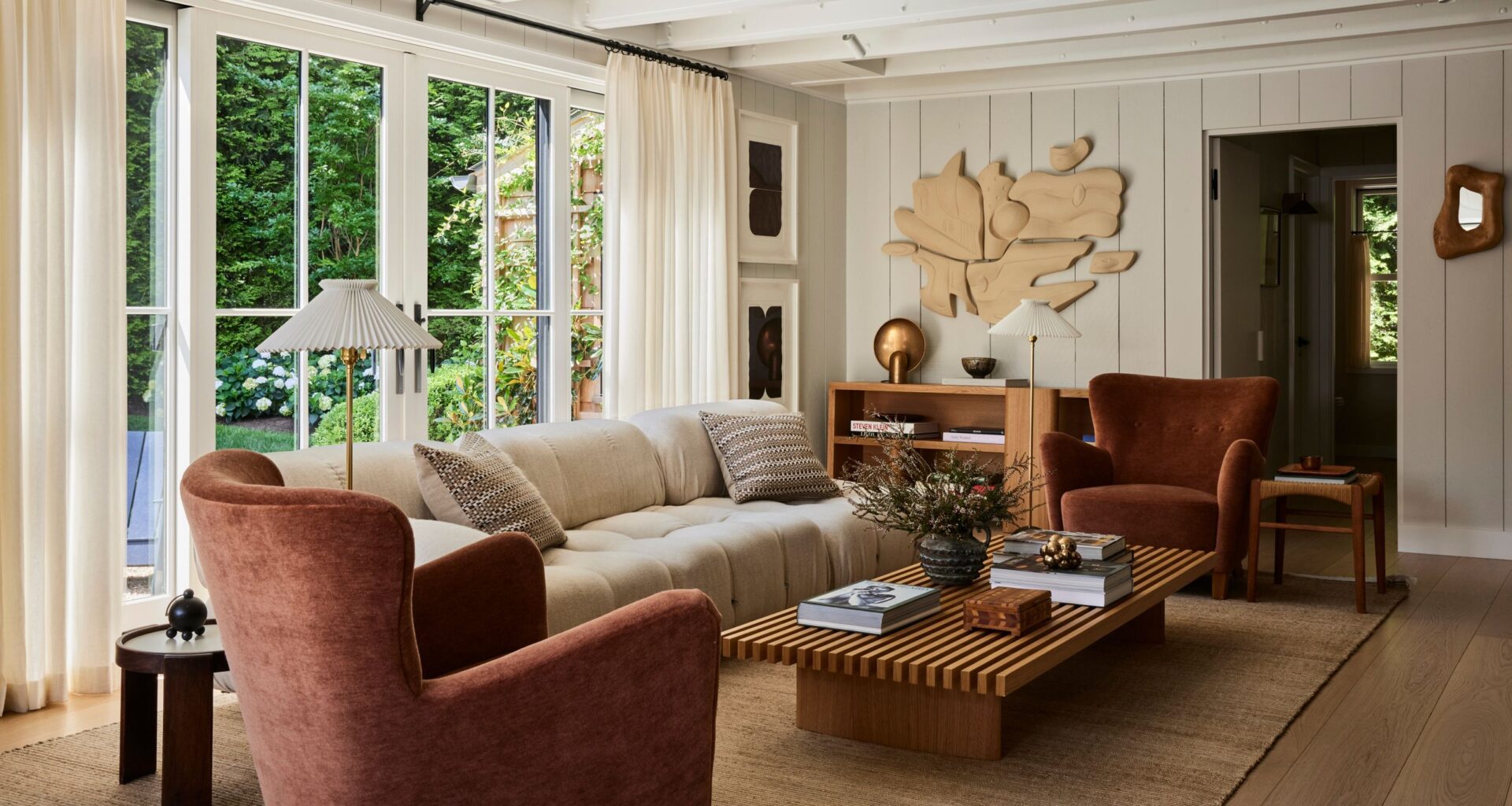 Living room with white panelled walls, wood floor, rust armchairs, cream sofa, striped marquetry coffee table