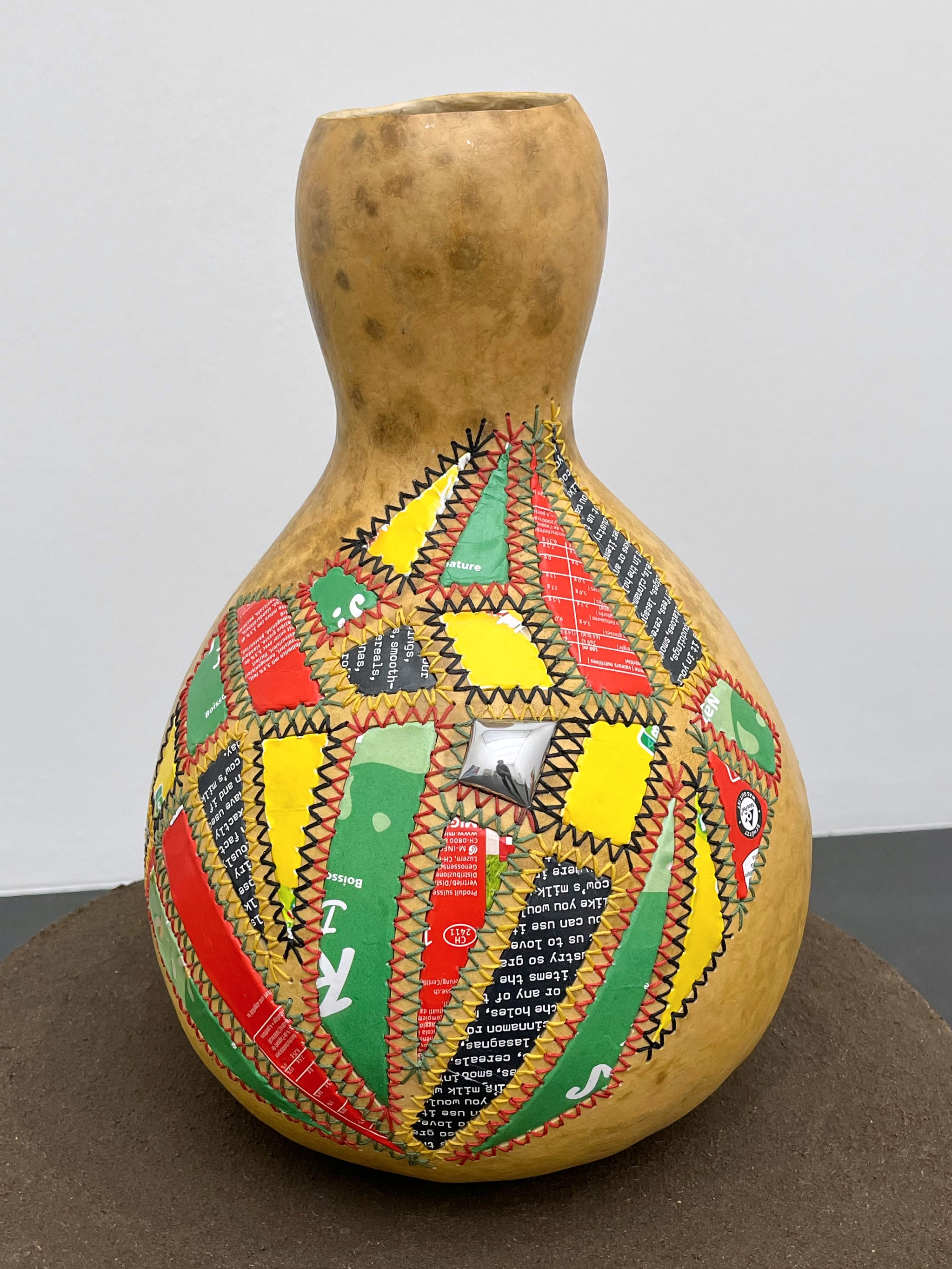 a gourd with colorful aluminum patches sewn on the side