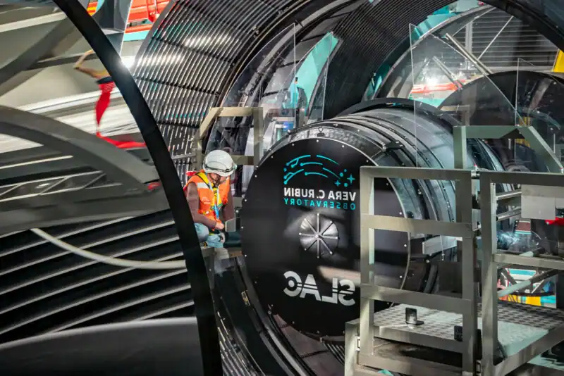 Closer image of a worker beside the large camera lens at the Vera Rubin Observatory.