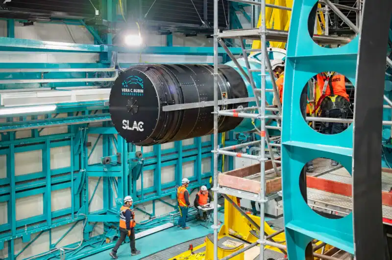 Image of construction workers working around a large camera lens. Vera C. Rubin Observatory. 