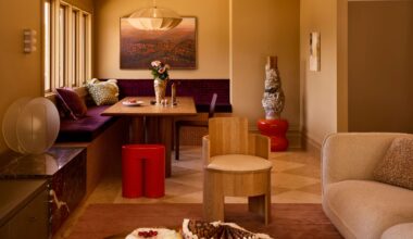 a neutral color drenched living area with a built in purple banquette seat and checkerboard flooring