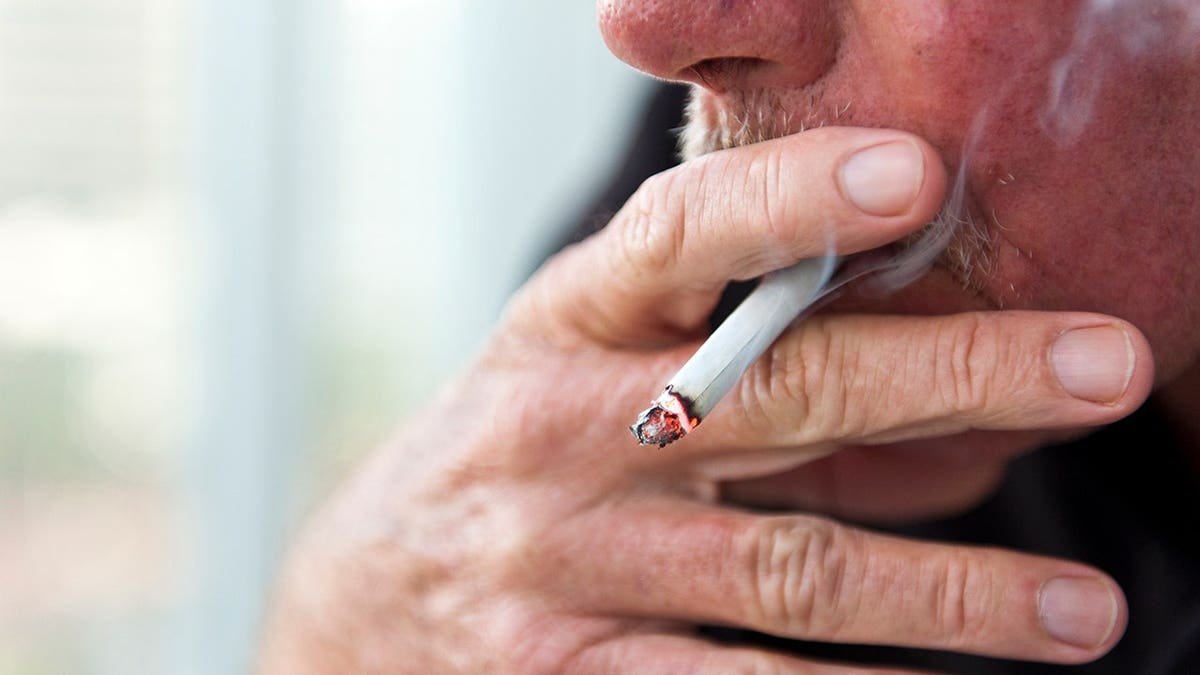 An old Caucasian man smoking a cigarette