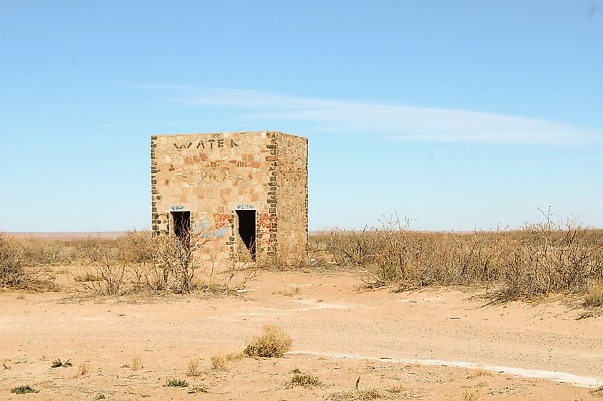 An abandoned wooden schoolhouse standing alone in the open New Mexico desert.
