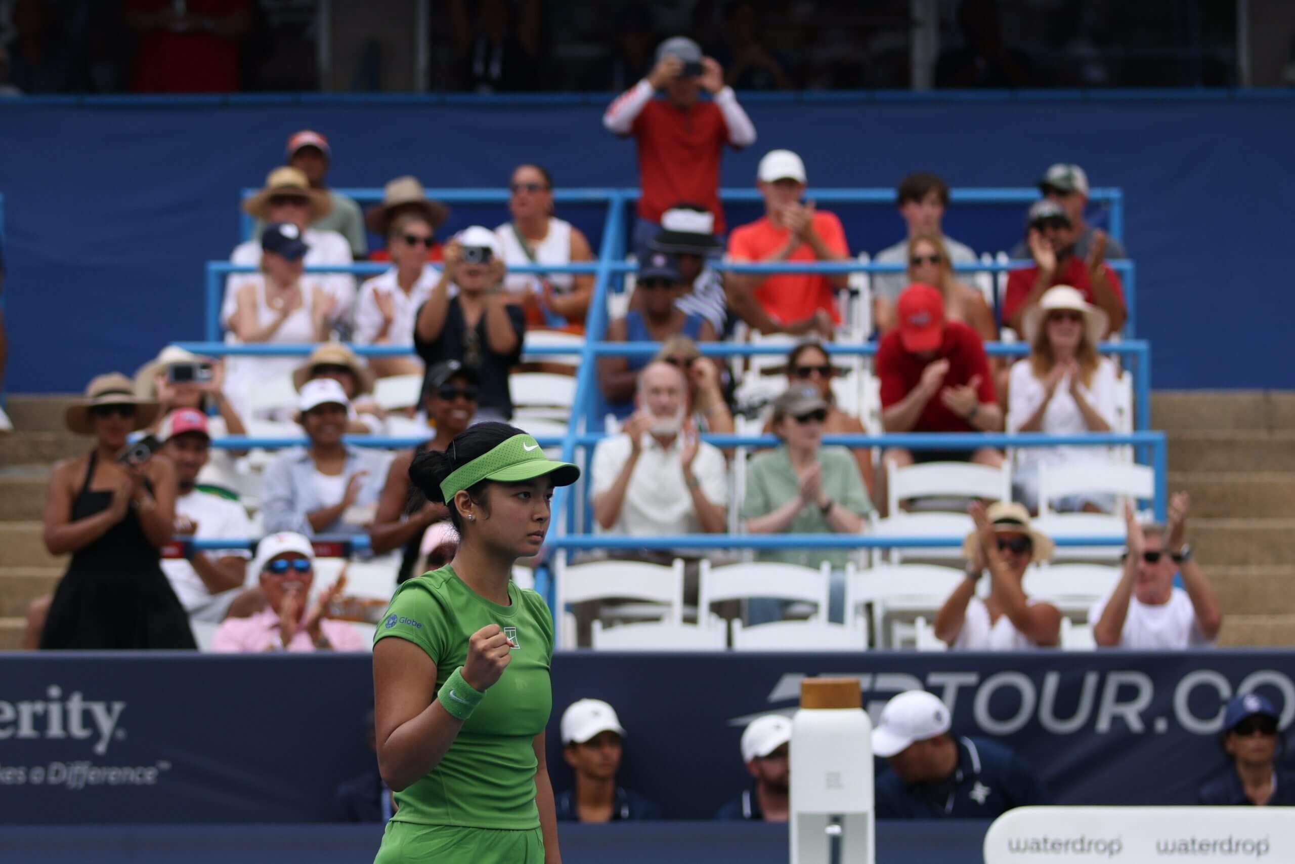 Alex Eala pumps her fist on a tennis court in front of fans.