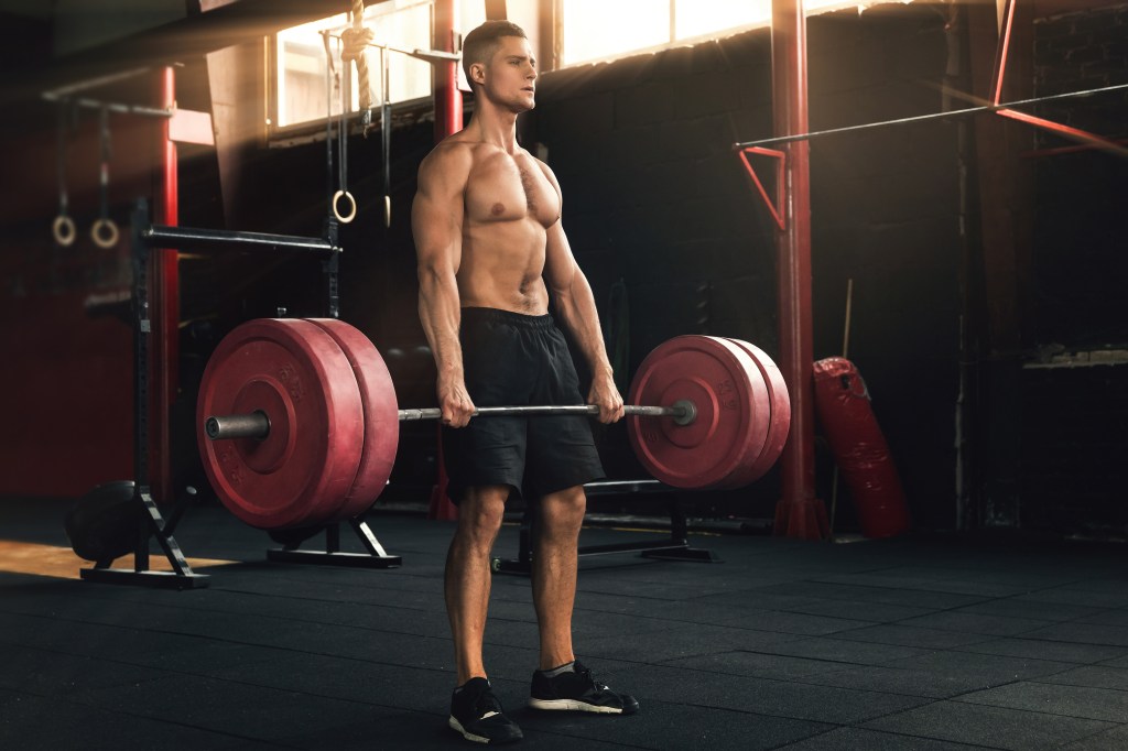 A muscular man performing a deadlift exercise in a gym.