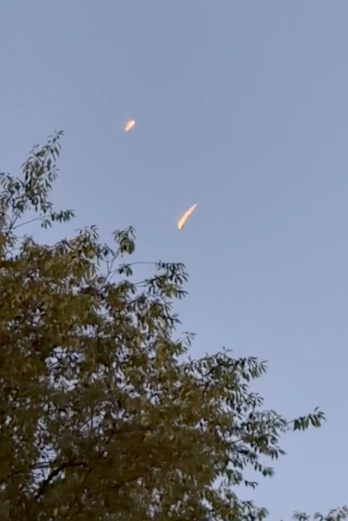Two meteors streaking across the evening sky over Connecticut, with a tree in the foreground.