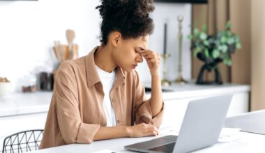 unhappy investor works on a laptop at a dining table.