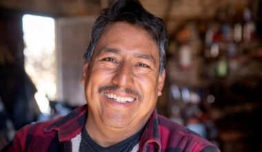 Someone in a flannel shirt is shown in close-up, smiling.