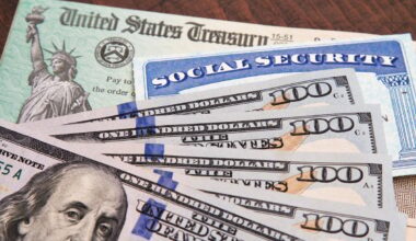 A U.S. Treasury check, a Social Security card, and U.S. currency spread over a wood surface.