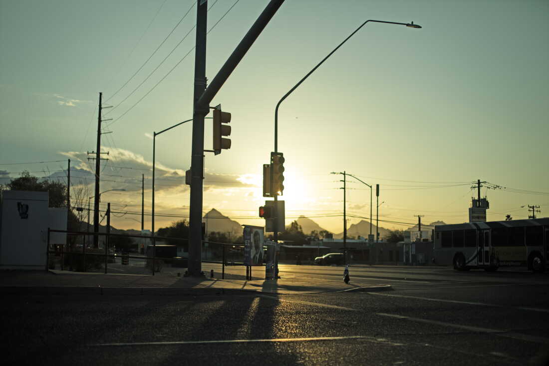 The sun shines behind a streetlight at an intersection in Tucson, Arizona.