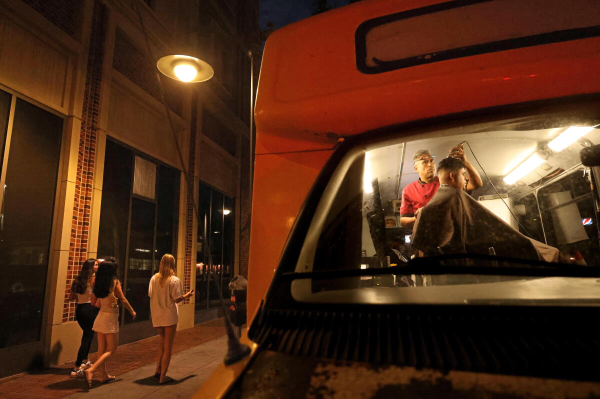 A barber cuts hairs in a school bus. 
