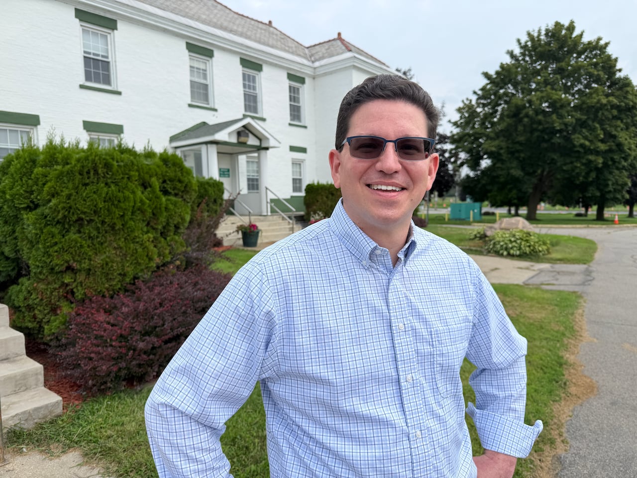 A man stands in front of a white building