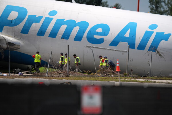Workers inspect an Amazon cargo plane two days after it overshot a runway at Miami International Airport, Tuesday, Sept. 8, 2026, in Miami. (AP Photo/Rebecca Blackwell)