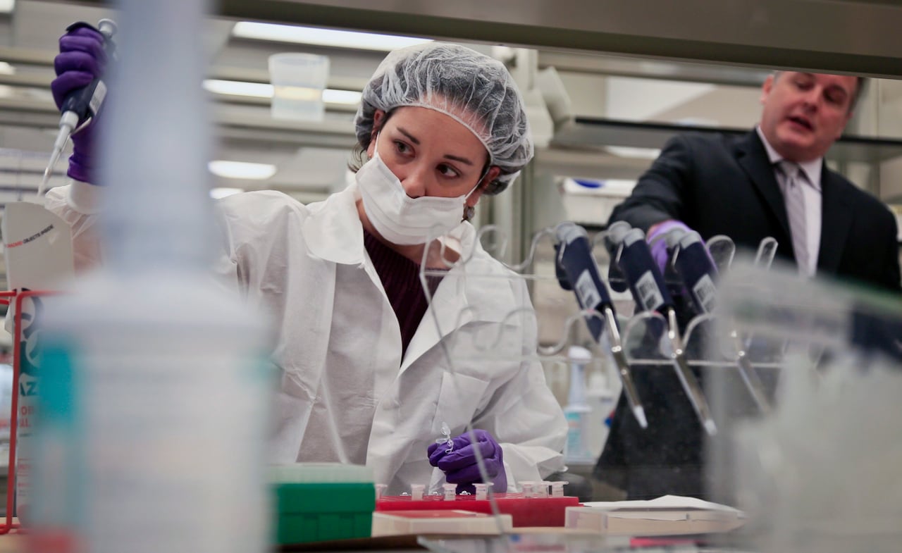 In this April 15, 2014 photo, Mark Desire, right, assistant director for forensic biology at the Office of Chief Medical Examiner, speaks as a criminalist, training in forensic science, prepares sample bone fragments for DNA testing.