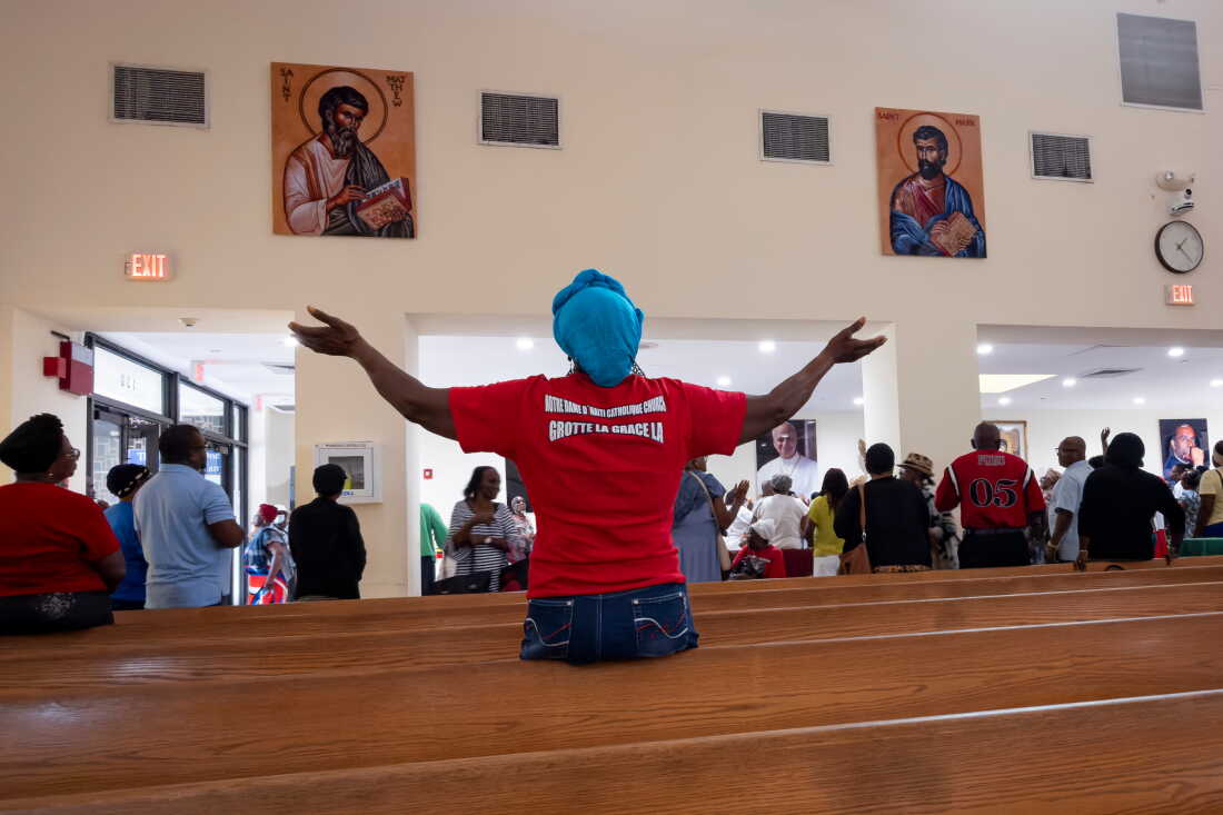 A woman raises her hands in prayer during a St. Michel prayer gathering at Notre Dame d'Haiti Catholic Church on Wednesday, Sept. 2, 2026, in the Little Haiti neighborhood of Miami, Fla.