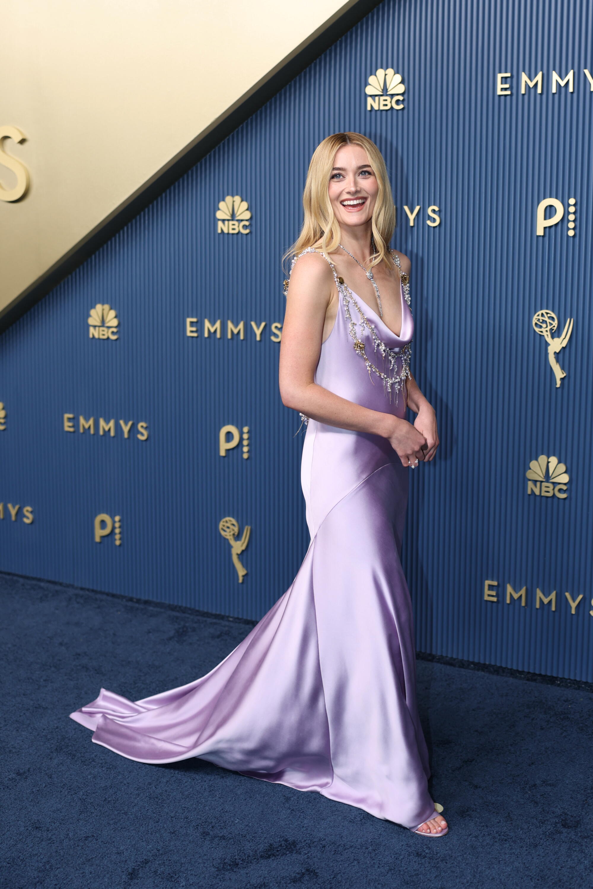 Sarah Pidgeon, wearing a purple gown, poses on the Emmys blue carpet. 