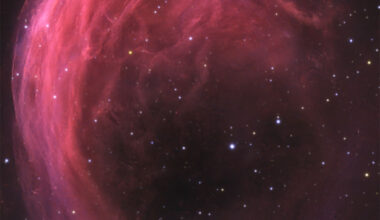 A starfield has a bright pink swirling nebula 
in it. The top part of the nebula shows much detail,
while the bottom part is mostly open.
Please see the explanation for more detailed information.