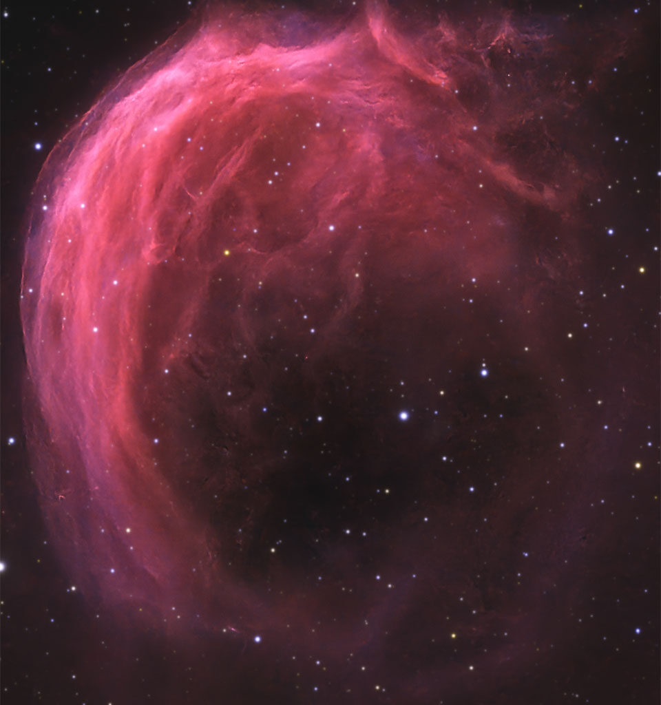 A starfield has a bright pink swirling nebula 
in it. The top part of the nebula shows much detail,
while the bottom part is mostly open.
Please see the explanation for more detailed information.