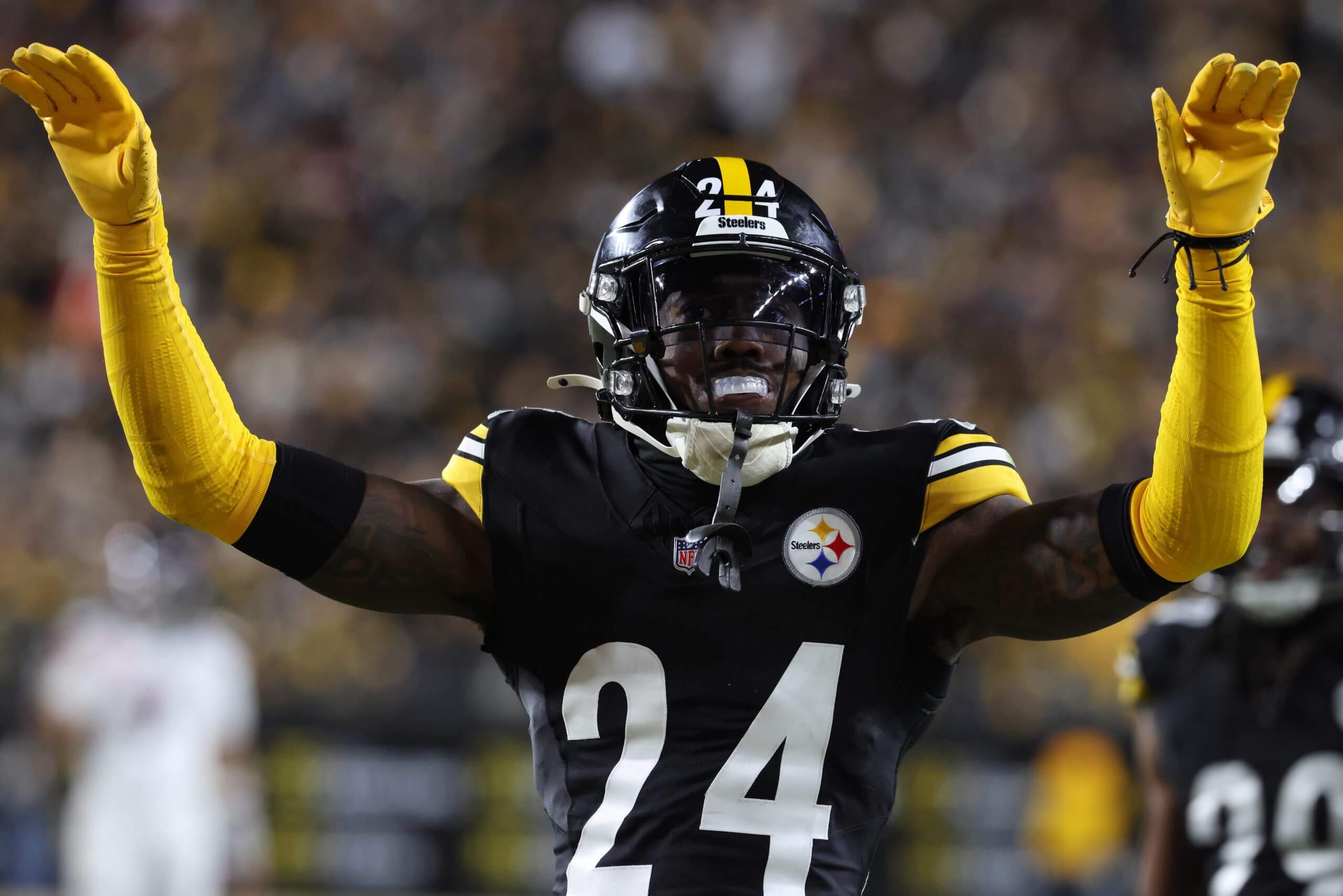 Pittsburgh Steelers cornerback Joey Porter Jr. raises his arms, with yellow sleeves and yellow gloves.