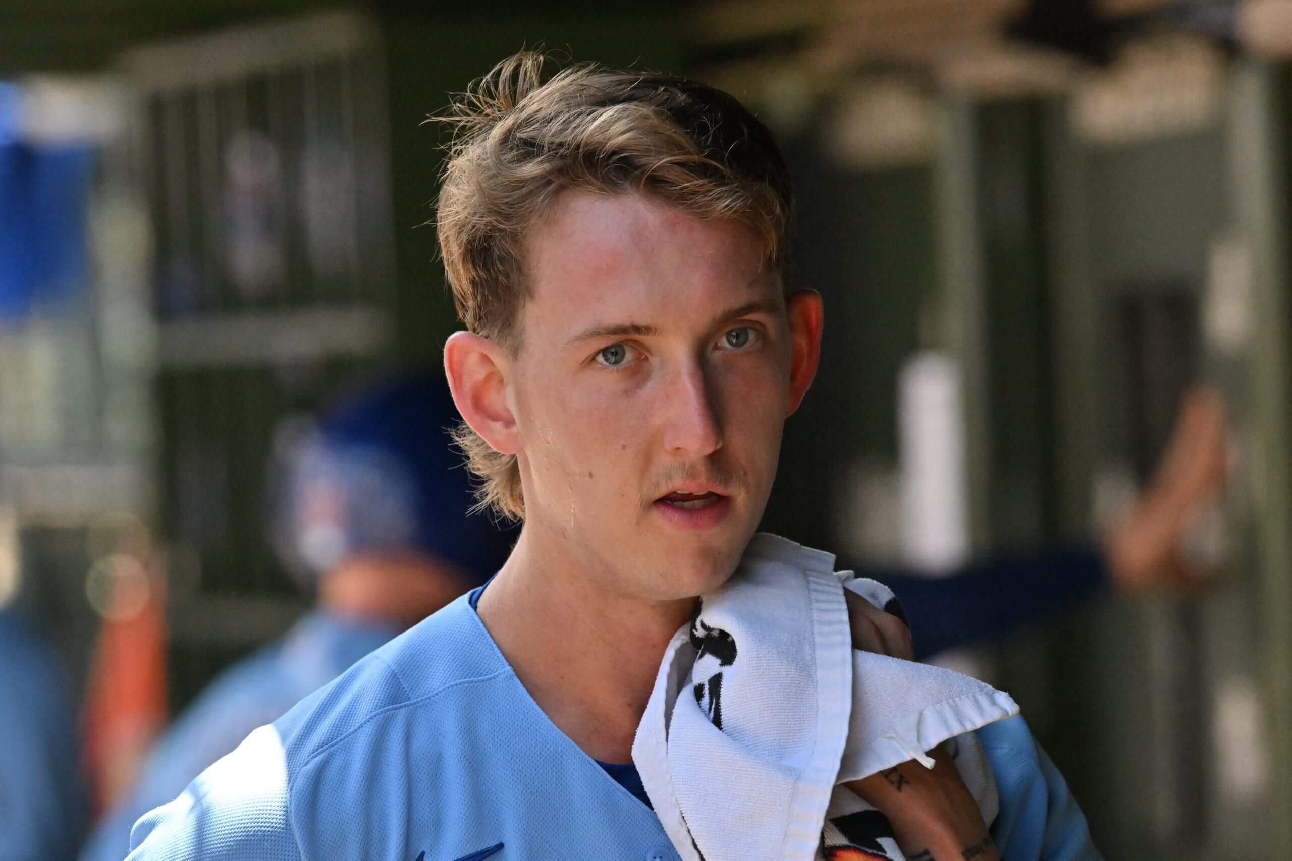 Ben Brown, with a towel over his left shoulder, looks on in a dugout.